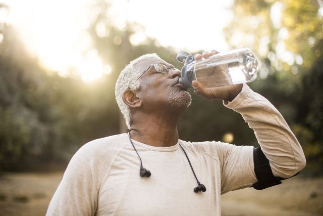 Older man with cancer exercises and drinks water.