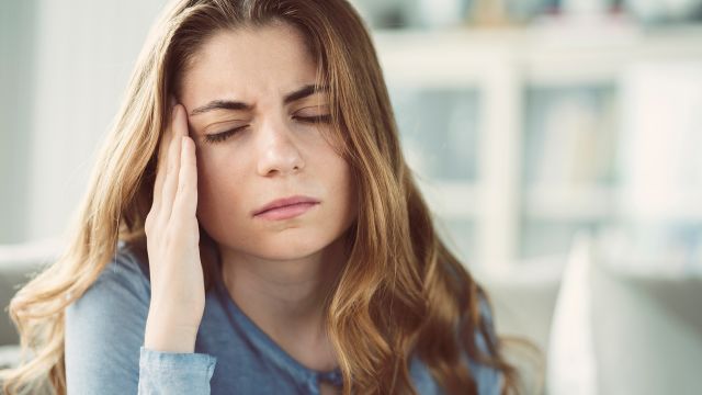 Woman with a headache holds her head.