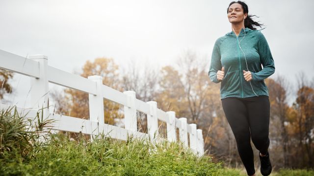 A smiling woman jogs as she experiences the emotional benefits of physical activity. Exercise and mood go hand-in-hand.