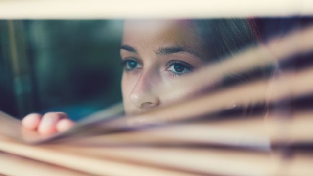 woman looking through blinds