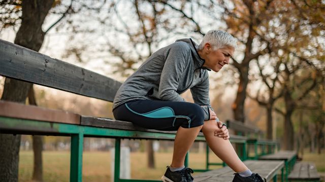 woman on a park bench with knee pain