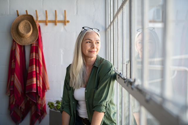 Woman staring out window looking hopeful