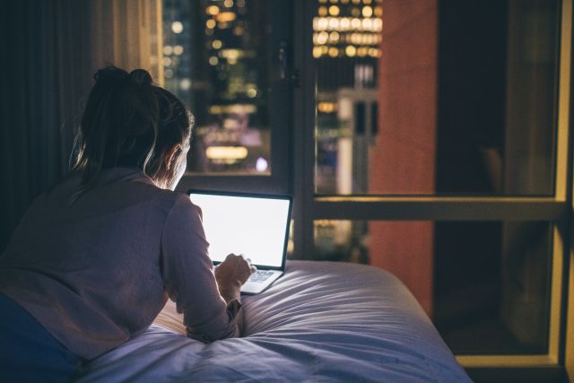 Woman on laptop at night in bed