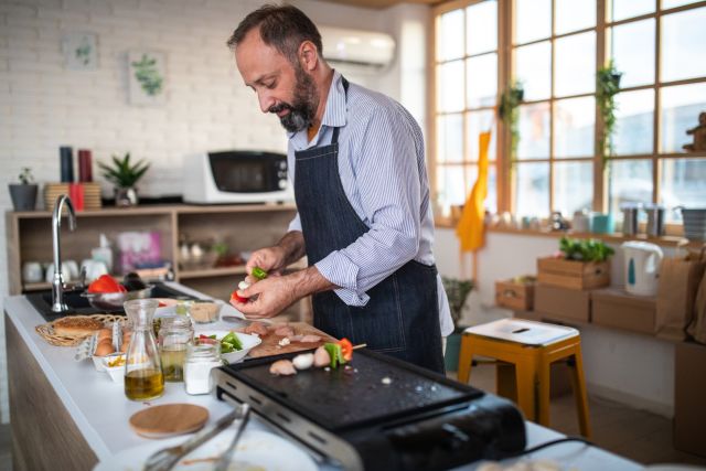 A man in a kitchen prepares a heart-healthy meal. Diet is an important part of managing high cholesterol.