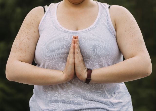 An overweight woman meditates to combat stress and improve weight loss.