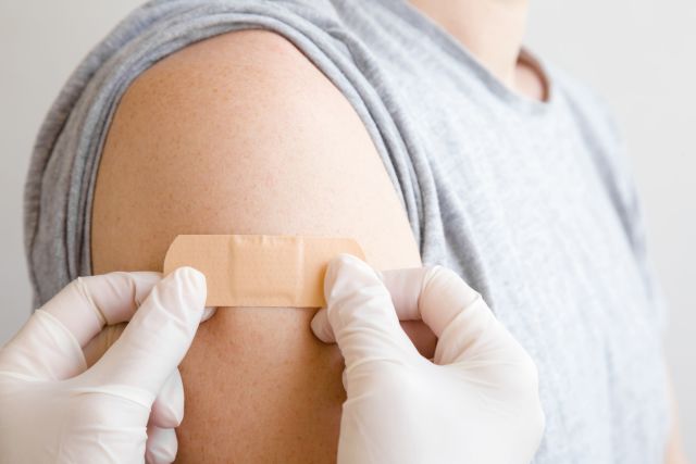 A nurse puts a bandage on a man’s arm after he receives one of the recommended vaccines for adults. 