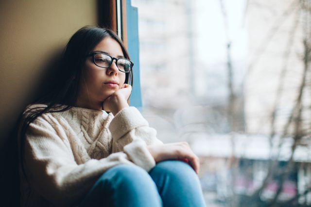 young woman staring out window