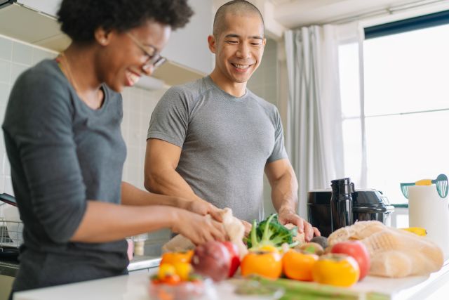 happy, fit Black woman and Asian man prepare healthy food in a kitchen