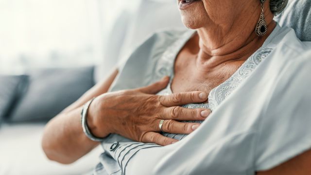 A woman rubs her chest from acid-reflux complications: What are the long-term complications of GERD?