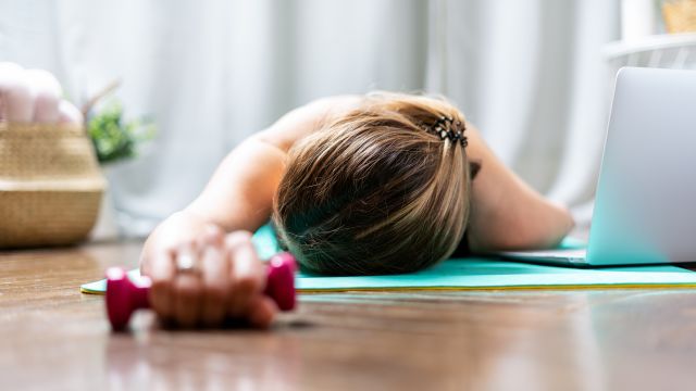 Woman rests on a yoga mat after a strenuous workout. 