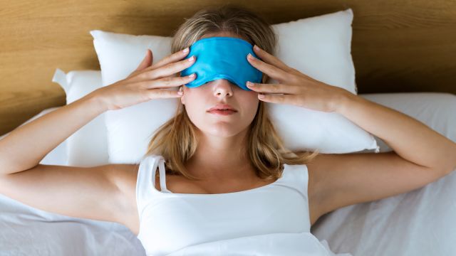 Woman wears a sleep mask in bed.