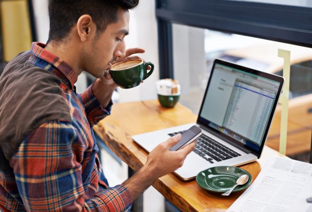 Young person at a laptop sipping coffee