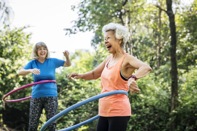 two elderly women use hula hoops for exercise