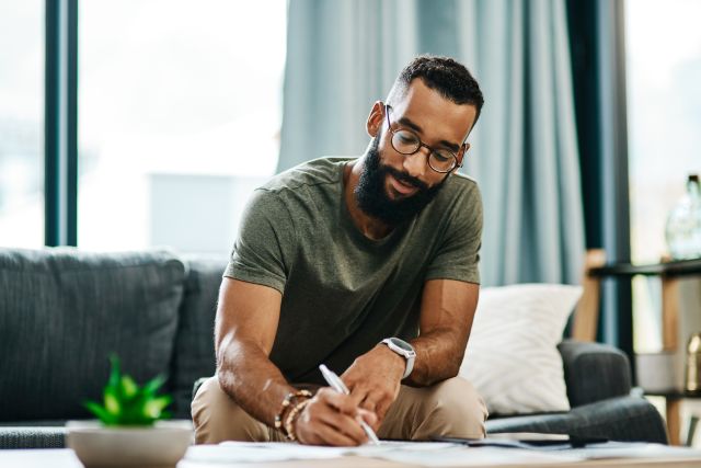 a young fit Black man makes notes in a journal about his goals and resolutions for the year 