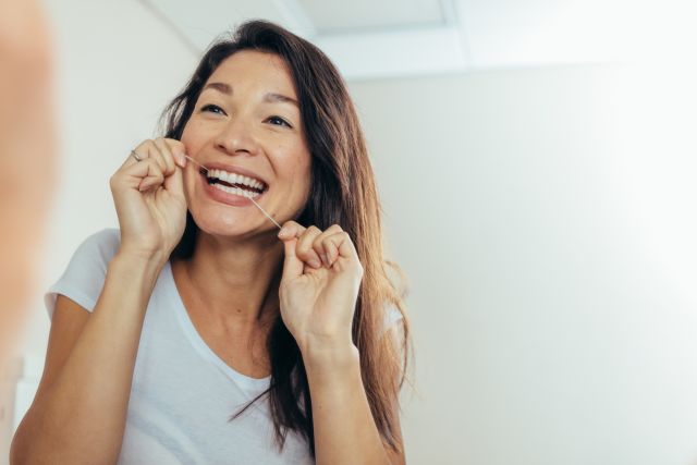 woman flossing at mirror