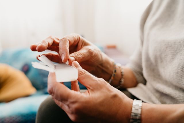 closeup shot of a pair of hands of a middle aged person selecting a pill from a pillbox