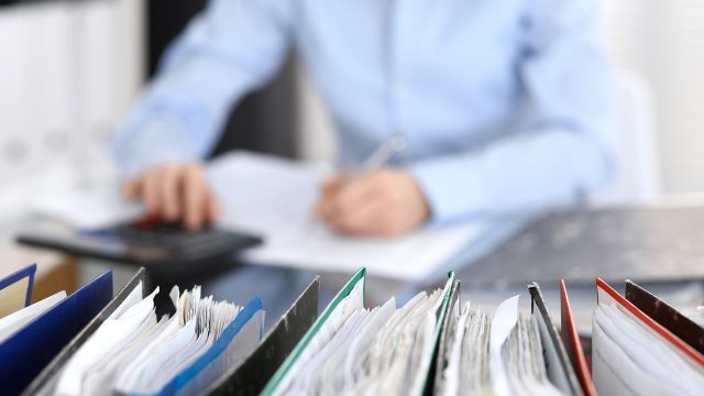 A woman in an office prepares financial paperwork. Oncology social workers can help people with MBC navigate the finances of cancer care.