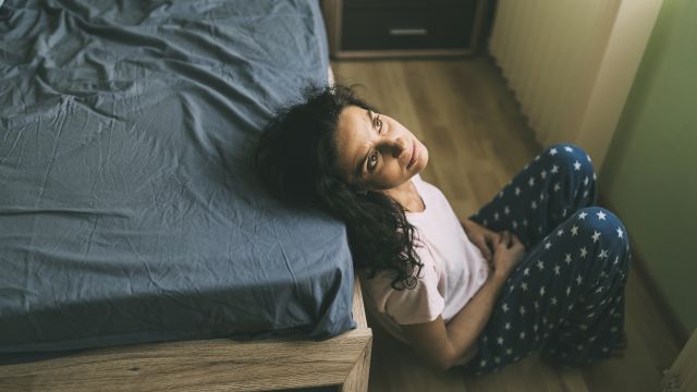 A woman sits on the floor in her bedroom. Many people with MS struggle with fatigue, weariness, and low energy as a result of the disease.