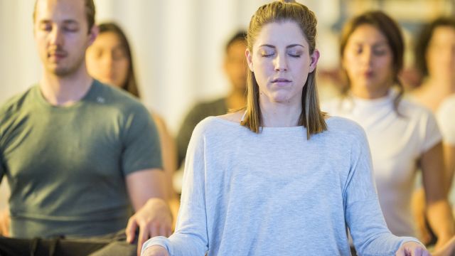 Young woman meditates with a group.
