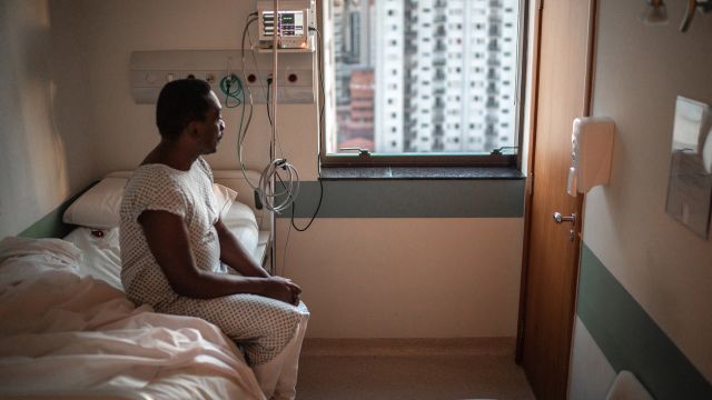 A senior man sits in his hospital room during a stay for lung cancer treatment.