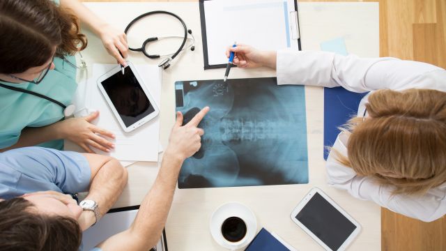 A team of healthcare providers examine an x-ray of the hip joint.