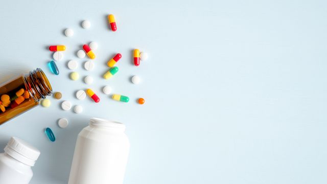 An assortment of pills and medicine bottles on a blue background. 