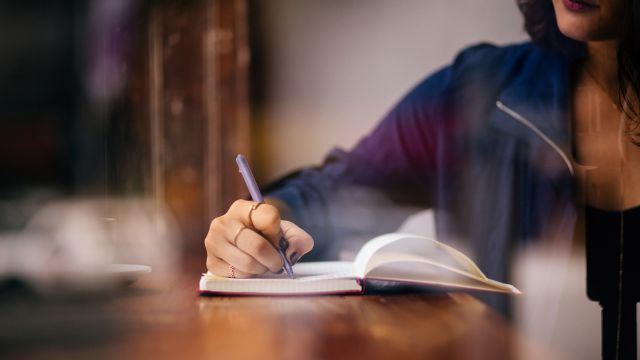 A woman writes in a journal. Keeping a journal of symptoms can be helpful when managing a chronic skin disorder.