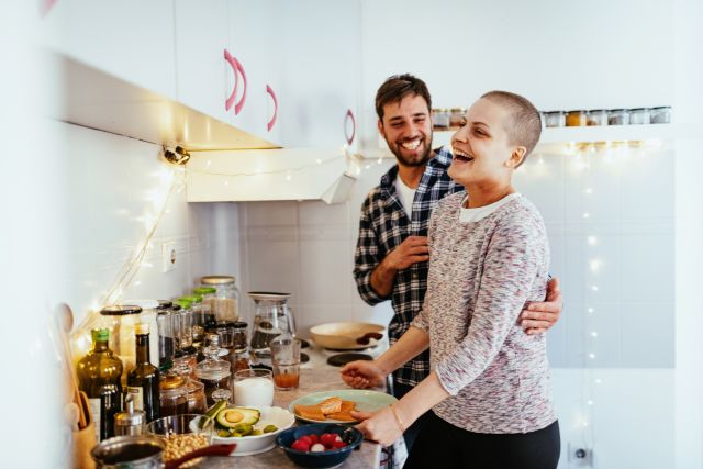 Day in a life of female cancer patient - couple cooking healthy food at home.