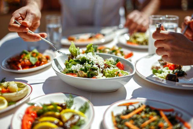 A table is filled with healthy, Mediterranean-inspired salads and appetizers, including a green salad in the foreground