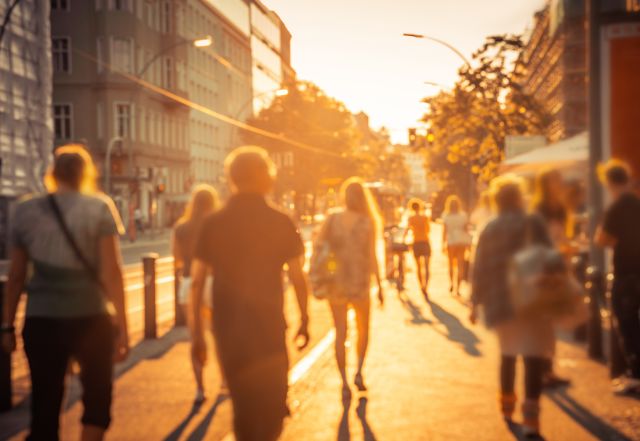 city dwellers walk down a city street during an extreme summer heat wave