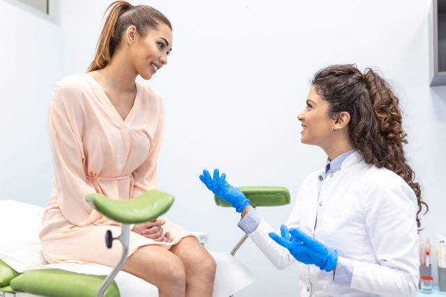 Young person sitting on an exam table and talking with a healthcare provider