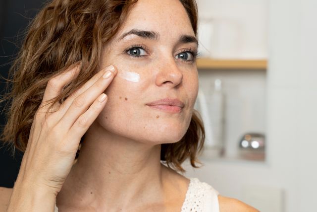 Close-up of woman applying cream to her face