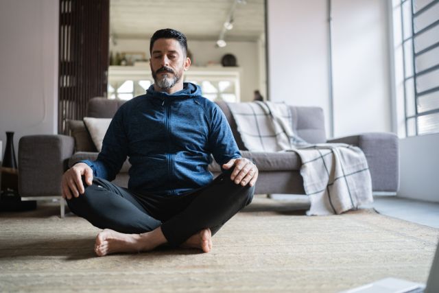 A man meditates at home to reduce stress. Taking steps to reduce stress can be helpful for a person living with bipolar disorder.