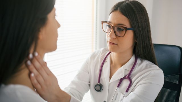 Female doctor checking the throat of a patient for signs of non-hodgkin's lymphoma.