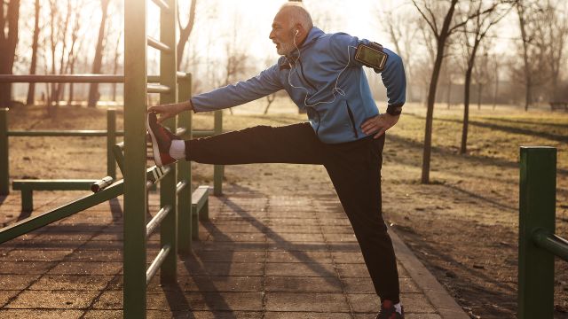 Older man stretching outside in the morning.