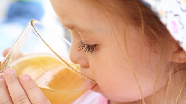 A child drinking juice, a drink often loaded with added sugars.
