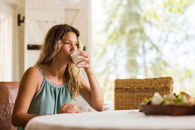 woman drinking a glass of skim milk for breakfast to curb hunger
