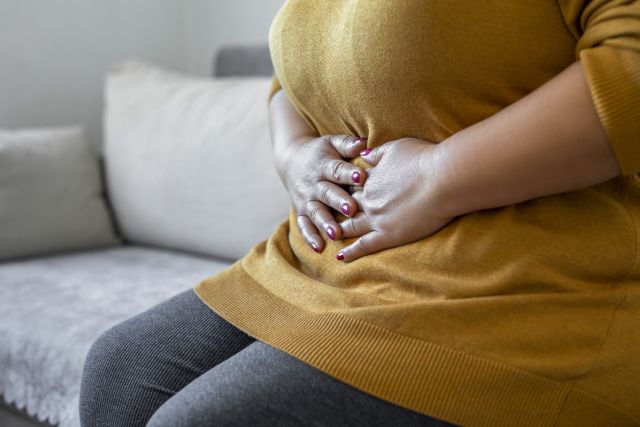 woman in yellow sweater with stomach pain