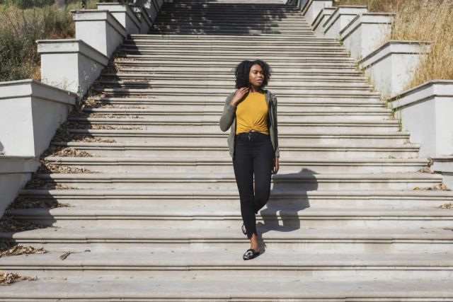 a young Black women goes for a walk in a city, walking down a long flight of outdoor stairs