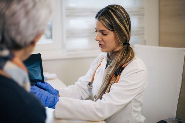 A senior woman speaks with her oncologist during an appointment.