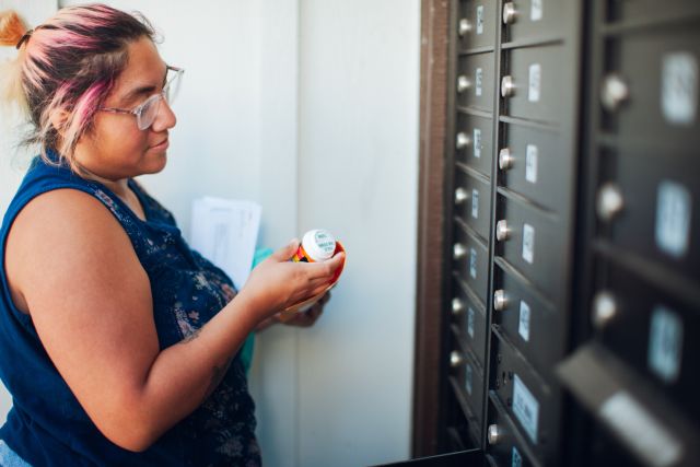 young woman receives prescription in her mailbox