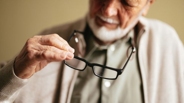 A senior man is having difficulty seeing despite using eye glasses. Age-related macular degeneration is a progressive condition that can cause greater vision impairment over time.