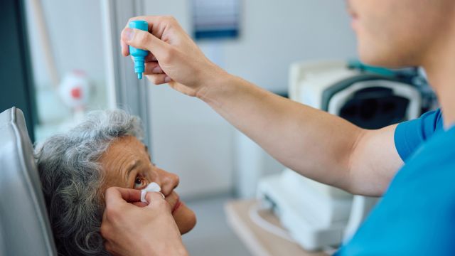 An ophthalmologist applies eye drops to the eye of a senior female patient. The eye may be dilated during an injection of medication to treat age-related macular degeneration.