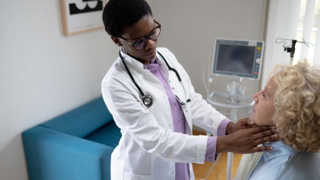 A doctor examines a patient's lymph nodes during an appointment. Blood cancers like lymphomas cause cause painless swelling in lymph nodes.