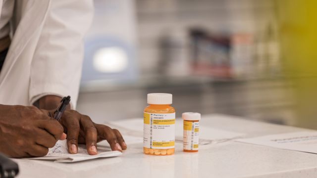 A pharmacist reviews a prescription. Treatment for Parkinson's disease psychosis may involve neuroleptic medications to ease hallucinations and other symptoms.