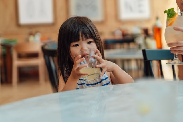 little girl drinks juice at a restaurant