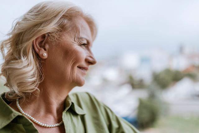 older adult wearing a hearing aid looking happy