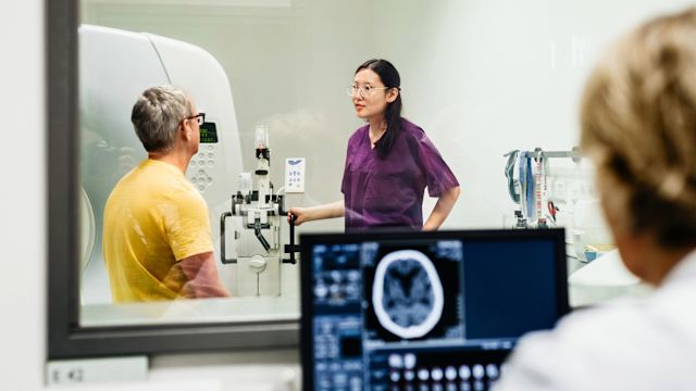 Healthcare providers guide a senior man through a CT scan as part of the diagnostic process for a neuroendocrine tumor.