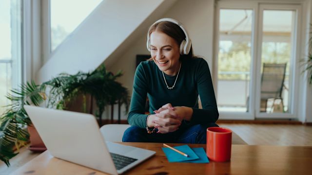 A young woman uses a laptop to participate in a virtual support group for people with CAH from her home.