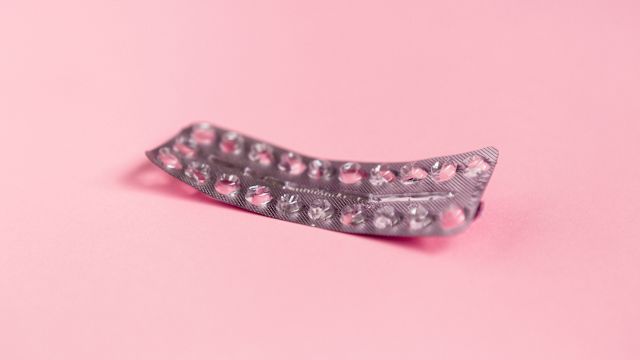 An empty package of birth control pills on a pink background.